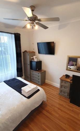 a bedroom with a bed and a flat screen tv at Midway Guest House in Torquay