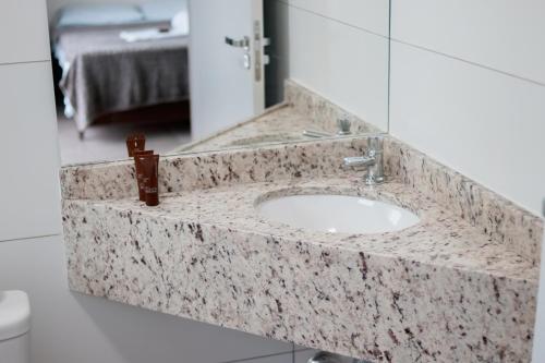 um lavatório de casa de banho com bancada em mármore em Pousada da Bia Praia em Penha