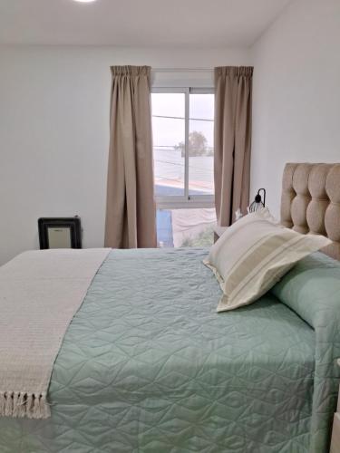 Un dormitorio con una cama grande con ventana. en CALA DEPARTAMENTO, en Alta Gracia