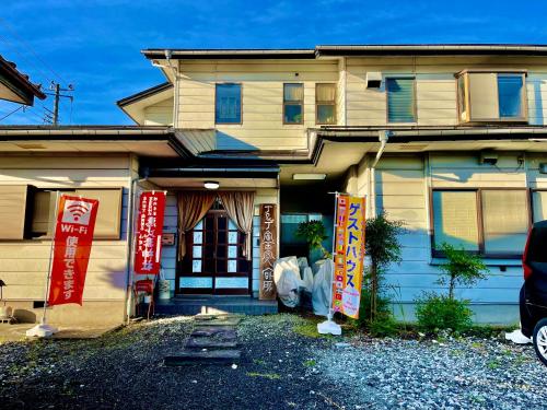 una casa con carteles delante de ella en T&T Fujiyama Guest House, en Fujiyoshida