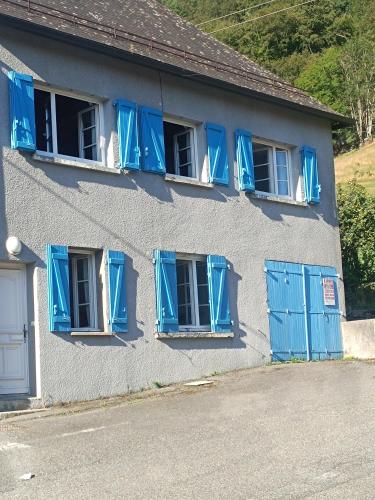 un bâtiment avec des fenêtres à volets bleus et des volets bleus dans l'établissement Gîte Ha-Py Family, à Campan