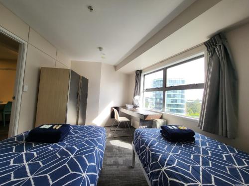 a room with two beds and a desk and a window at Empire Apartments in Auckland