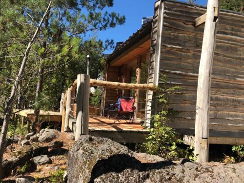 a log cabin with a deck and a chair on the porch at Domos Altos de Lircay in San Clemente