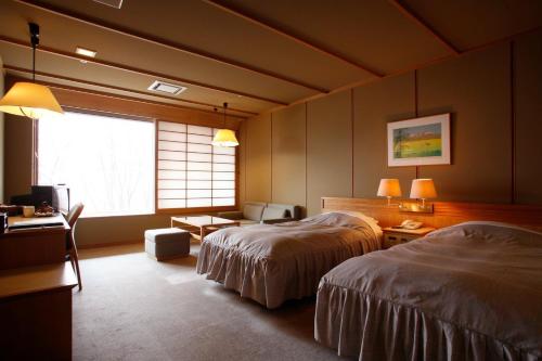 千歳市にある支笏湖第一寶亭留翠山亭のベッド2台と窓が備わるホテルルームです。