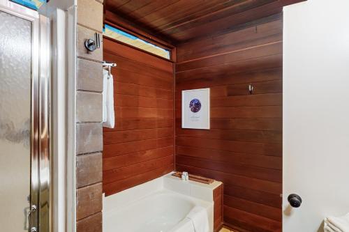 a bathroom with wooden walls and a bath tub at Modern Pines Hideaway in Crestline