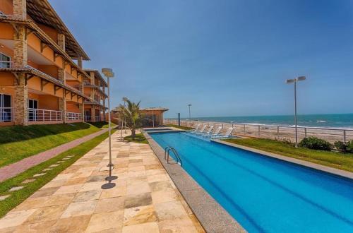 una piscina frente a un edificio con el océano en Dream Away Uruaú Beach Residences, en Beberibe