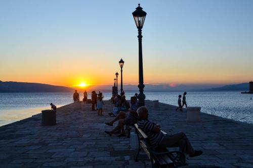 a group of people sitting on benches watching the sunset at Apartment Bellavita Senj in Senj