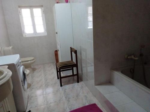 a bathroom with a toilet and a tub and a chair at MG - Aluguer de quartos in Felgueiras