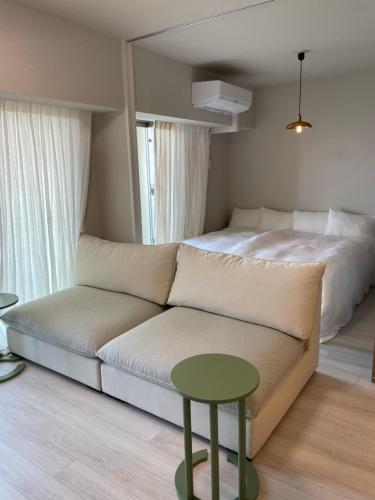 a bedroom with a bed and a couch and a table at 1204 ブランシエラ那覇曙プレミスト in Nakanishi
