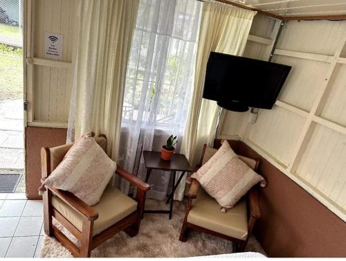 um quarto com 2 cadeiras e uma televisão de ecrã plano em Tico Bed & Breakfast La Fortuna em La Fortuna