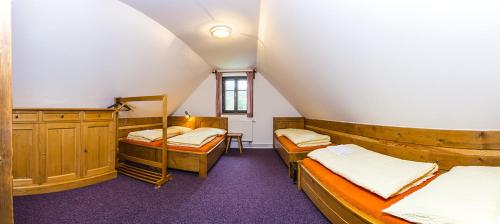 Cette chambre mansardée comprend 3 lits et une table. dans l'établissement Horská chata Skácelka, à Rokytnice nad Jizerou