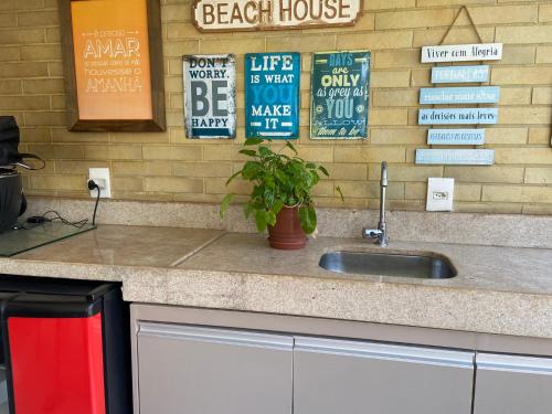 a kitchen counter with a sink and signs on the wall at apartamento vista mar in Aquiraz