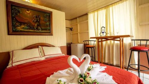 Dois cisnes brancos numa cama vermelha num quarto em Tico Bed & Breakfast La Fortuna em La Fortuna