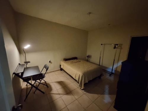 a bedroom with a bed and a table and chair at Departamento Victoria in Saltillo