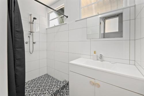 La salle de bains blanche est pourvue d'un lavabo et d'un miroir. dans l'établissement Entire Beach House on Bribie Island, à Bongaree