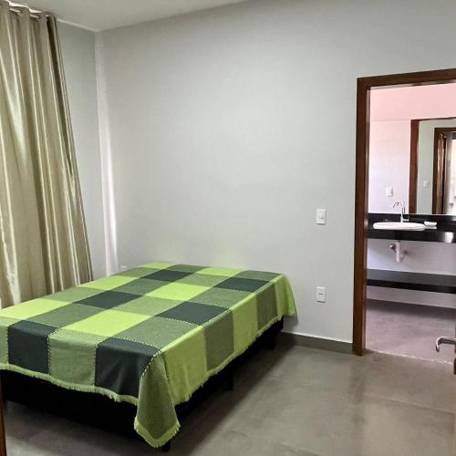Zimmer mit einem Bett mit einer karierten Decke in der Unterkunft Residência Prado in Capitólio