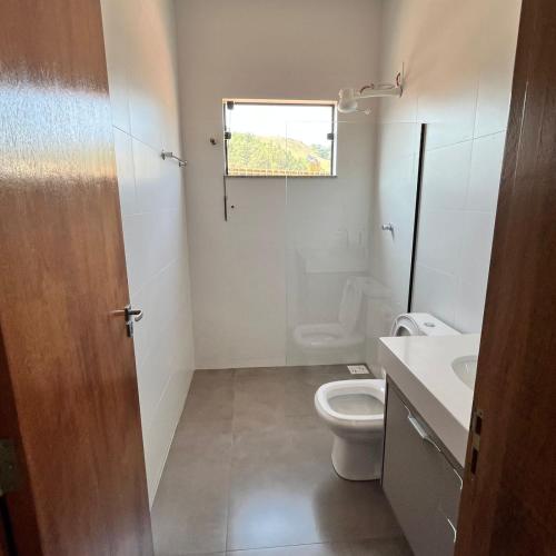 ein Bad mit einem WC, einem Waschbecken und einem Fenster in der Unterkunft Residência Prado in Capitólio
