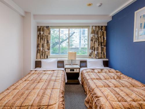 two beds in a room with blue walls and a window at Hotel Koryukaku in Tokyo