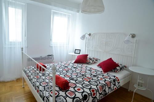 Dormitorio blanco con cama con almohadas rojas en Golden Gate Apartment Zadar, en Zadar