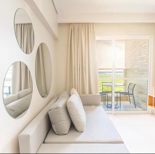 a white living room with a couch and a mirror at Apto Salinas Exclusive Resort, 2 quartos in Salinópolis