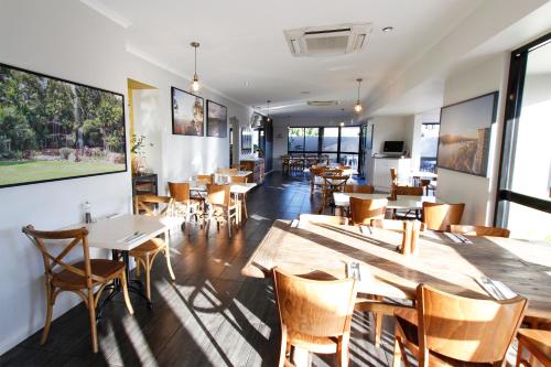 un restaurant avec des tables et des chaises en bois ainsi que des fenêtres dans l'établissement The Stirling Motel, à Rockhampton