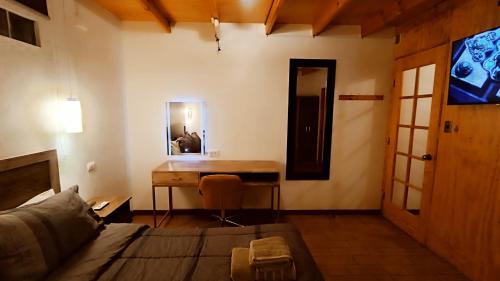 a room with a desk and a bed and a table at Hostal Yurak in San Pedro de Atacama