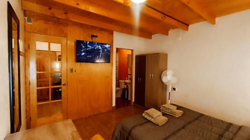 聖佩德羅·德·阿塔卡馬的住宿－Hostal Yurak，卧室配有一张床,墙上配有电视