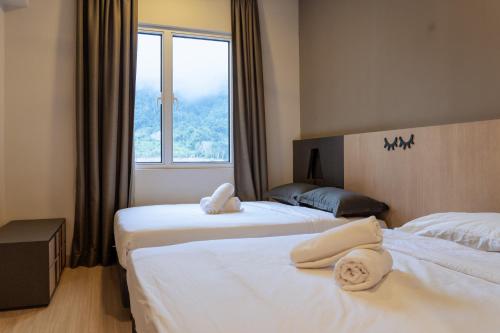 two beds in a hotel room with a window at Windmill Upon Hills Premium Suite By Rapi Stay in Genting Highlands