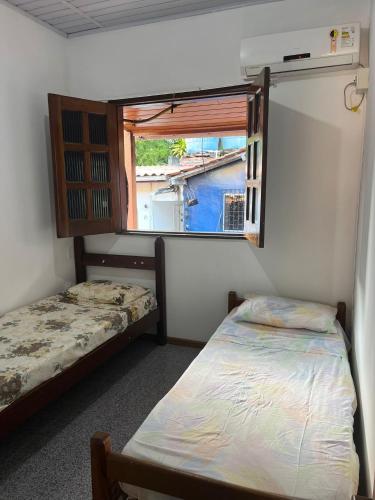 two beds in a small room with a window at Casa Vermelha in Morro de São Paulo