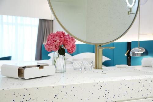 a table with a mirror and pink flowers on it at Asia International Hotel Guangdong in Guangzhou
