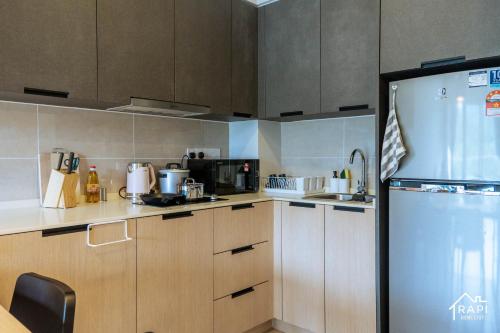 a kitchen with wooden cabinets and a stainless steel refrigerator at Windmill Upon Hills Premium Suite By Rapi Stay in Genting Highlands