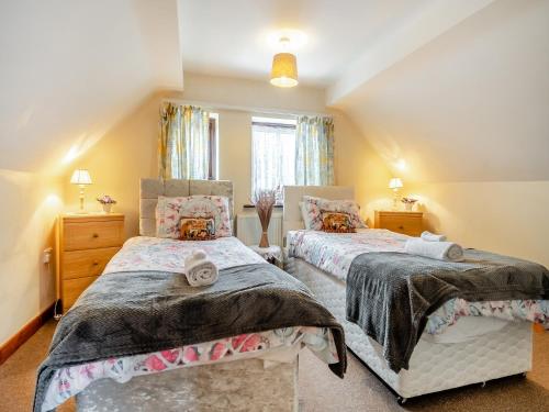a bedroom with two beds and a window at Pear Tree Cottage in Banham