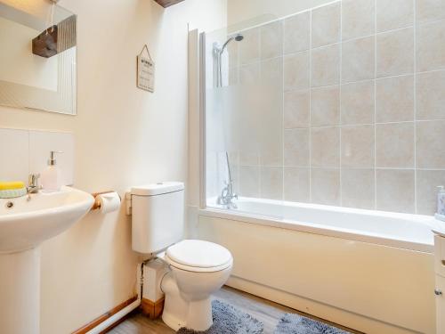 a bathroom with a toilet and a sink and a tub at Pear Tree Cottage in Banham
