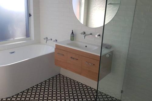 a bathroom with a sink and a tub and a mirror at 'Ampleforth East' in Albury
