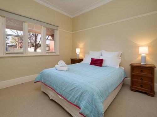 a bedroom with a bed with two night stands and two windows at 'Ampleforth East' in Albury
