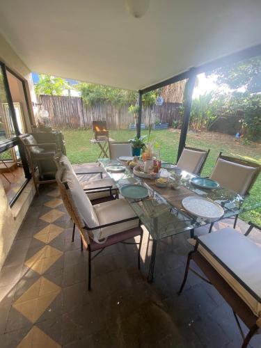 uma sala de jantar com uma mesa de vidro e cadeiras em Cairns Homestay em White Rock