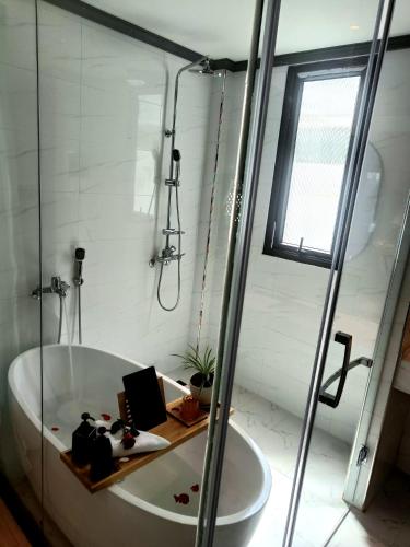 a white bathroom with a bath tub and a window at LuangPrabang Pearl Hotel in Luang Prabang