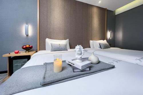 a hotel room with two beds with a candle on a table at Yzhi Hotel - West Sports Road Metro Station in Guangzhou