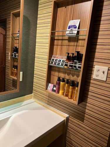 a bathroom with a tub and a shelf with bottles at ホテルアシュエル in Minatomachi