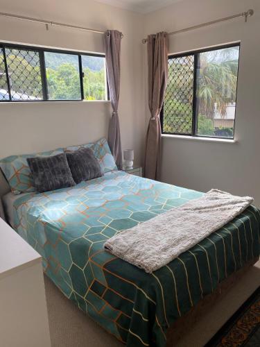 a bed in a bedroom with two windows at Cairns Homestay in White Rock