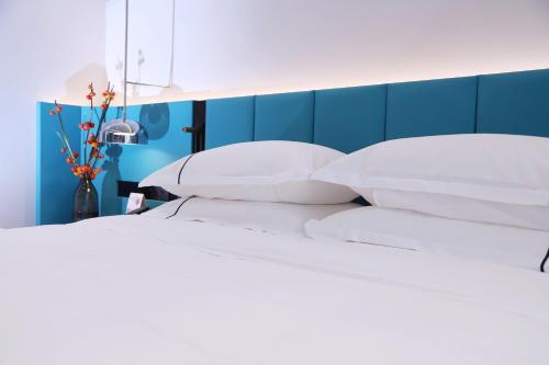 a bed with white pillows and a blue wall at Asia International Hotel Guangdong in Guangzhou