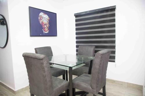 a dining room with a glass table and chairs at Dabb Apartments in Ilorin