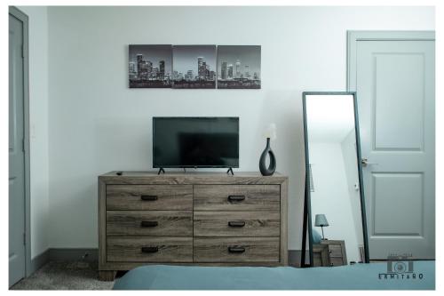 a bedroom with a dresser with a television on it at Trendy Midtown Apartment in Houston