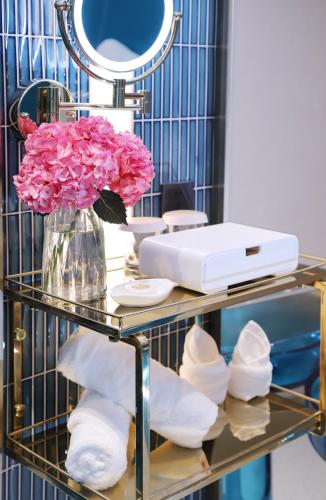 a glass table with a vase of pink flowers and towels at Asia International Hotel Guangdong in Guangzhou