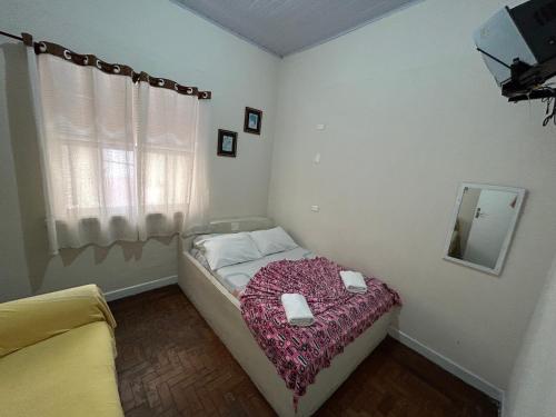 a small bedroom with a bed and a mirror at Pousada da Praia in São Vicente