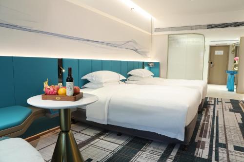 a hotel room with two beds and a table with a bowl of fruit at Asia International Hotel Guangdong in Guangzhou