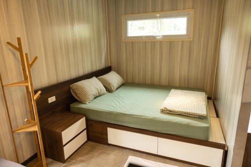 a small bed in a small room with a window at Halo Retreat in Hòa Bình
