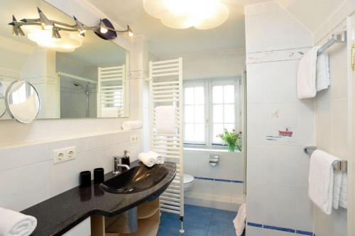 een badkamer met een wastafel, een toilet en een spiegel bij Ferienhaus-Hoppe-Wohnung-01 in Westerland