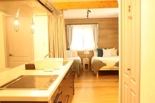 a room with a bed and a kitchen with a sink at SAUNA FOREST CABIN 軽井沢 御代田 A棟 zen-asobi in Oiwake