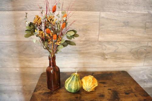 a brown vase with flowers and acorns on a table at SAUNA FOREST CABIN 軽井沢 御代田 A棟 zen-asobi in Oiwake